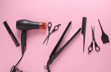 Pembe arka planda saç şekillendirme için düz saç modelleme aletleri ve aksesuarları vardı. Üst görünüm