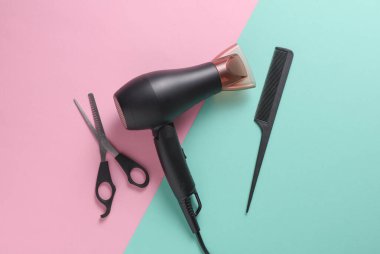 Pembe arka planda saç şekillendirme için düz saç modelleme aletleri ve aksesuarları vardı. Üst görünüm