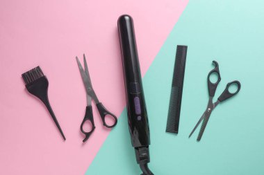 Pembe arka planda saç şekillendirme için düz saç modelleme aletleri ve aksesuarları vardı. Üst görünüm