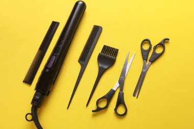 Sarı arka planda saç şekillendirme için düz saç modelleme aletleri ve aksesuarları vardı. Üst görünüm