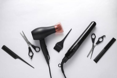 Beyaz arka planda saç şekillendirme için düz saç şekillendirme aletleri ve aksesuarları vardı. Üst görünüm