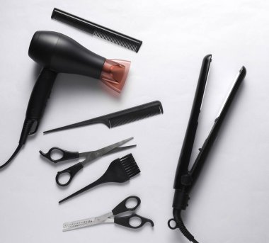 Beyaz arka planda saç şekillendirme için düz saç şekillendirme aletleri ve aksesuarları vardı. Üst görünüm