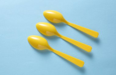 Mavi arka planda sarı plastik kaşıklar. Üst görünüm