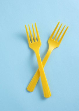 Mavi arka planda sarı plastik çatallar. Üst görünüm