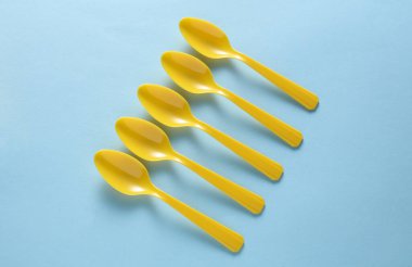 Mavi arka planda sarı plastik kaşıklar. Üst görünüm