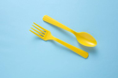 Sarı plastik çatal ve sarı arka planda kaşık.