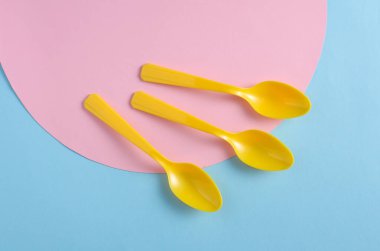 Mavi arka planda sarı plastik kaşıklar. Yaratıcı yerleşim