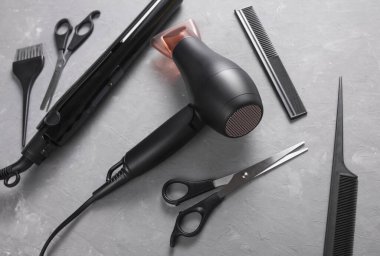 Gri arka planda saç şekillendirme için düz saç şekillendirme aletleri ve aksesuarları vardı. Üst görünüm