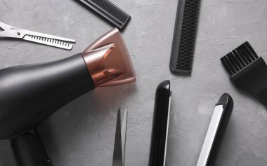 Gri arka planda saç şekillendirme için düz saç şekillendirme aletleri ve aksesuarları vardı. Üst görünüm