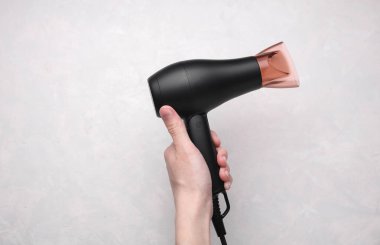 Gri arka planda saç kurutma makinesi var.