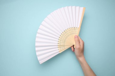 Mavi arka planda el ele tutuşan geleneksel Asyalı el yelpazesi