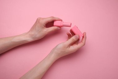 Pembe arka planda ruj tutan eller