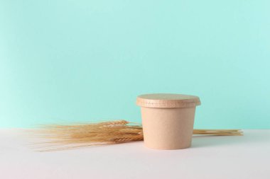 Çevre kartonundan yiyecek kutusu ve nane yeşili arka planda buğday kulakları.