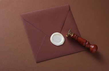 Balmumu mühürlü zarf ve kahverengi arka planda klasik damga. Hediye çeki, düğün davetiyesi.