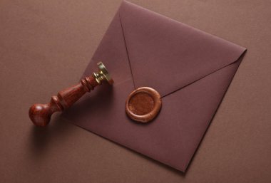 Balmumu mühürlü zarf ve kahverengi arka planda klasik damga. Hediye çeki, düğün davetiyesi.