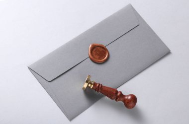 Balmumu mühürlü zarf ve gri arka planda vintage damga. Hediye çeki, düğün davetiyesi.