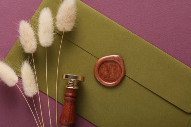 Yeşil zarf, balmumu mühür ve eski pul, lagurus çiçekleri. Hediye çeki, düğün davetiyesi.