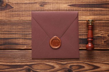 Balmumu mühürlü zarf ve ahşap arka planda eski pul. Hediye çeki, düğün davetiyesi.