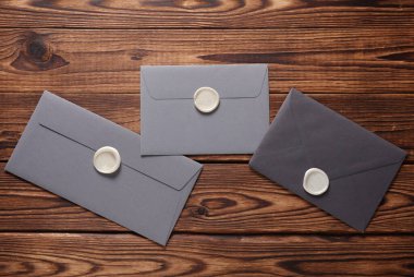 Ahşap zemin üzerinde balmumu mühürler olan zarflar. Hediye çeki, düğün davetiyesi.