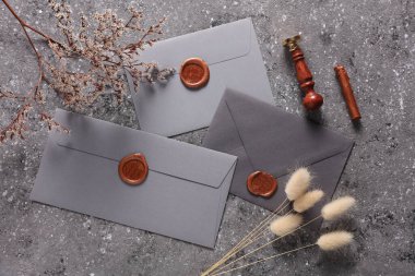 Balmumu mühür ve eski pullu zarf, çimento arka planda kuru çiçekler. Hediye çeki, düğün davetiyesi.