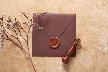 Balmumu mühür ve eski pullu zarf, çimento arka planda kuru çiçekler. Hediye çeki, düğün davetiyesi.