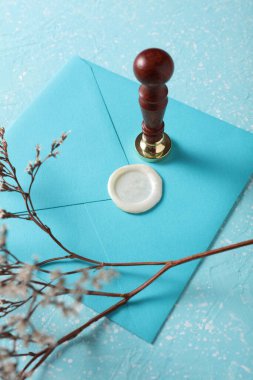 Balmumu mühür ve eski pullu zarf, mavi beton arka planda kuru çiçekler. Hediye çeki, düğün davetiyesi.