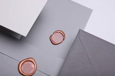 Üzerinde balmumu mühürler ve gri arka planda kartlar olan yüzen zarflar. Hediye çeki, düğün davetiyesi. Yaratıcı yerleşim
