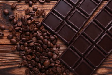 Tahta arka planda kahve çekirdekleri olan koyu çikolata.