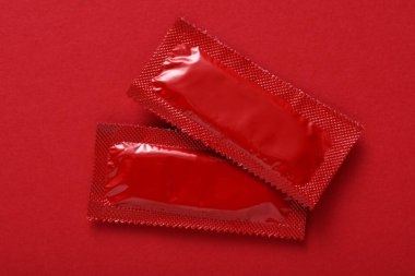 Kırmızı arkaplanda prezervatif paketleri