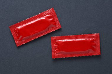 Koyu gri arka planda prezervatif paketleri