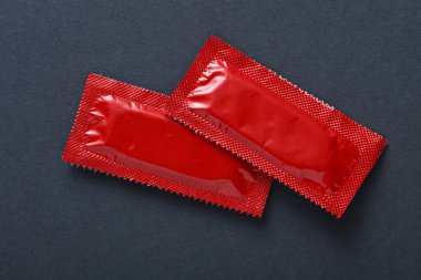 Koyu gri arka planda prezervatif paketleri