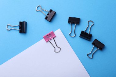 Gülümseyen yüz kablosuz sayfa ve mavi arkaplanda yüzsüz klasörler olan bir ataç. Liderlik, eşsizlik, kariyer gelişimi. İş konsepti.