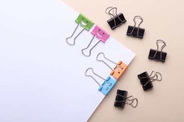 Gülümseyen yüzlü ataçlar ve bej arka planda kağıt kağıtlar. İş konsepti