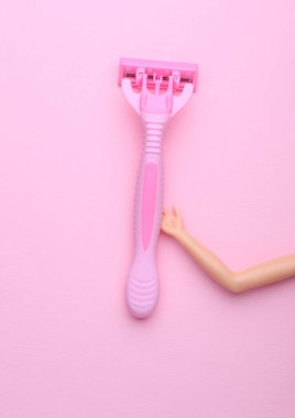 Oyuncak el pembe arka planda plastik jilet tutuyor.