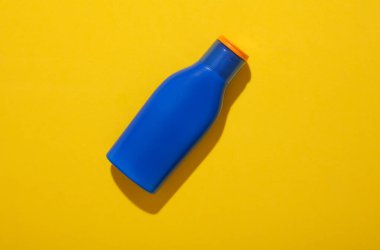 Sarı arkaplanda bir şişe güneş kremi