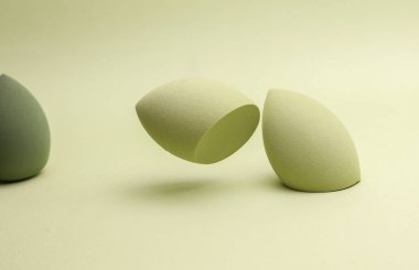 Yüzen yumurta makyaj süngeri. Yeşil arka planda temel için blender. Asgari güzellik kavramı