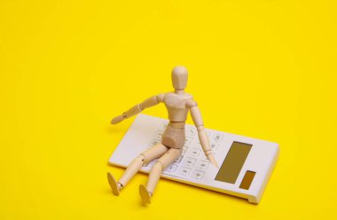 Sarı zemin üzerinde tahta kukla olan hesap makinesi