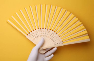 Sarı arka planda plastik el vantilatörü. 