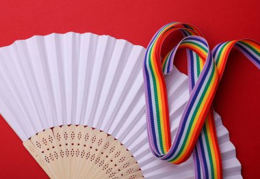 Kırmızı arkaplanda fan olan LGBT gökkuşağı kurdelesi