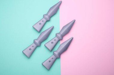 Oyuncak ninja bıçakları mavi pembe arka plana fırlatıyor.