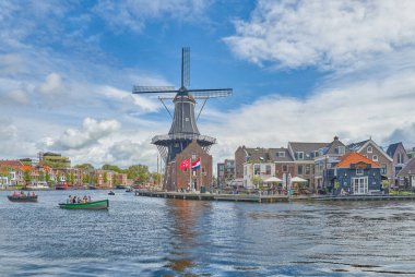 Haarlem, Hollanda - 13 Ağustos 2023: Spaarne nehrinde Adriaan yel değirmeni olan köy turist botu tarafından geçildi