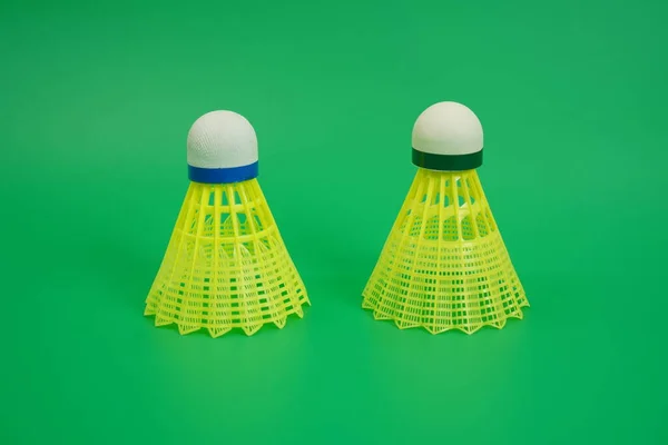 The picture shows a yellow plastic training shuttlecock on a green background, isolated.
