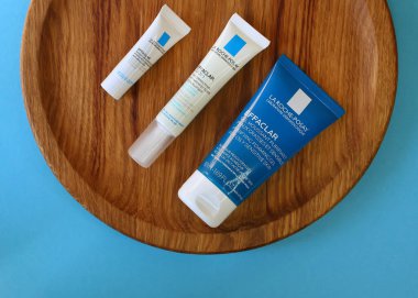 KYIV, UKRAINE - 8 EPTEMBER 2022: Üç La Roche Posay mini ürününden oluşan set. Fransız kozmetik markası. Ahşap meşe plaka ve mavi arka plan. Üst Manzara. Seçici odak.