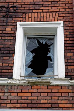 Tuğla duvarda beyaz çerçeveli kırık bir pencere.