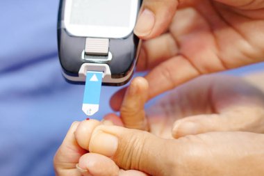 Doktor kan şekeri seviyesini ölçmek için parmak ucuna eldiven takıyor..