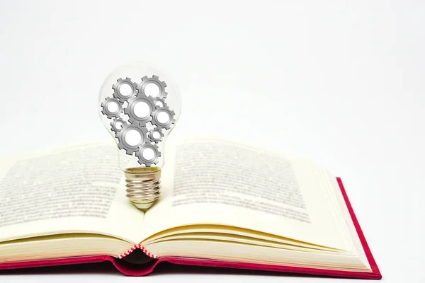 Light bulb with gear or cogwheel is placed on book. Concept of knowledge, wisdom, new ideas and creativity.