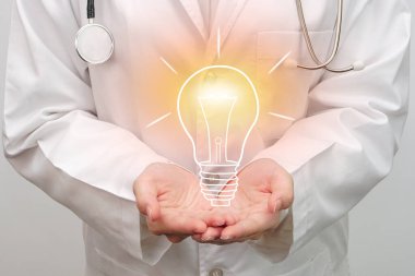 Doctor holding virtual light bulb in hand. Medical technology, medical futuristic and holographic concept.