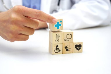 Hand holding a wooden block cube with healthcare medical icon symbol. Medical and health concept.