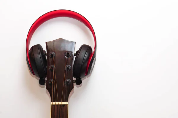 Acoustic guitar and the headphones on white background. Concept of leisure, relaxation and music.