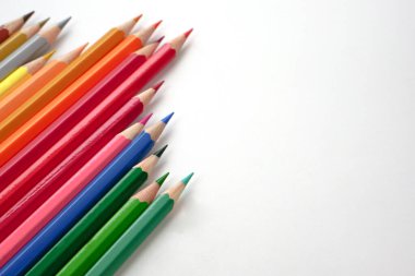 Beyaz zemin üzerinde renkli kalemlerin veya pastelin üst görünümü (Seçici odak). Öğrenme, öğrenme ve sunum kavramı.